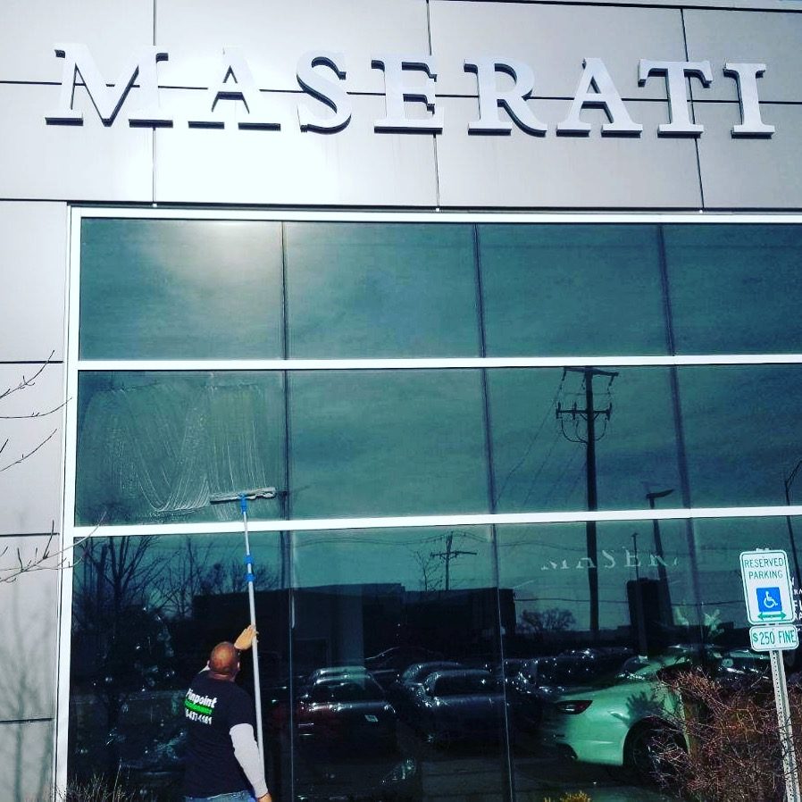 A person standing in front of a maserati dealership.