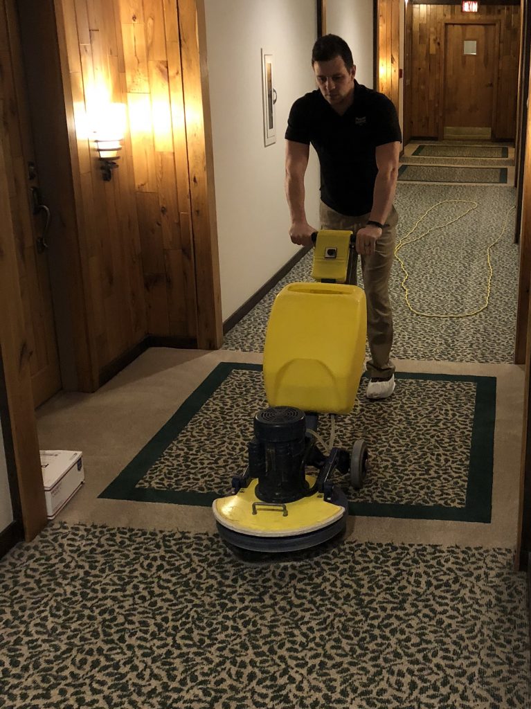 A man is cleaning the floor with a machine.