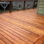 A deck with wood flooring and metal railing.