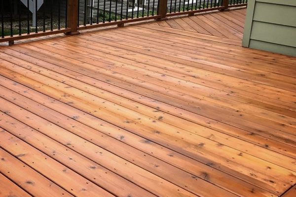 A deck with wood flooring and metal railing.